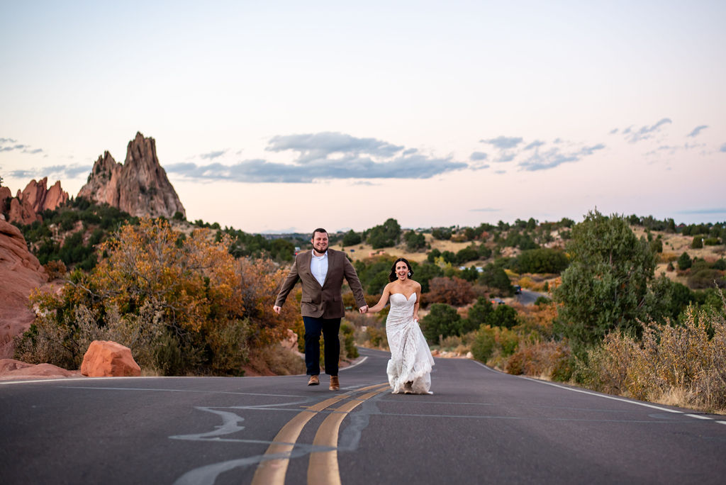 Bride and Groom run up the rock at Garden of the Gods park. Both are laughing as they race each other. 