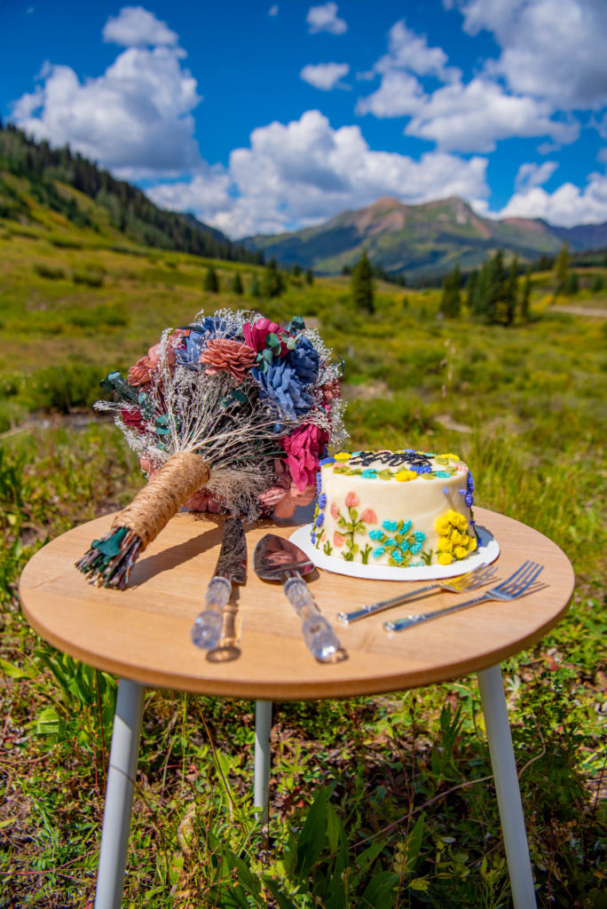 wedding cake and bridal bouquet decorate a table during an elopement in Crested Butte