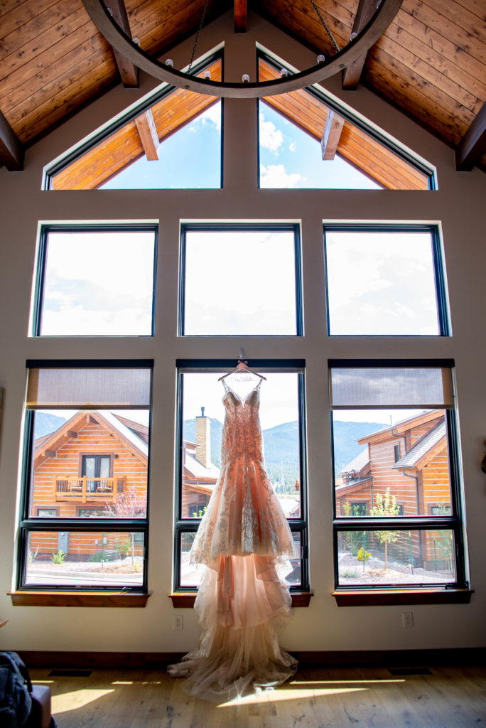 dress hangs up in front of a huge window in a cabin at Estes Park