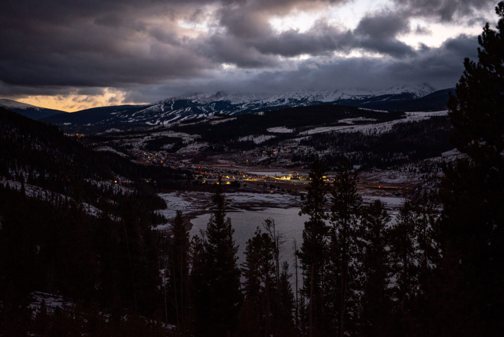 a dark photo of the mountains that surround Breckenridge. city lights twinkle in the low light of the sunset