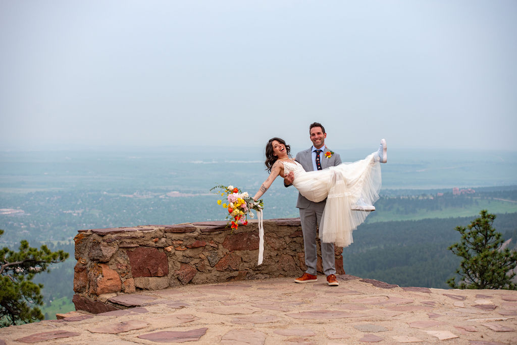 Groom sweeps the bride off her feet and they smile at the Boulder wedding photographer. 