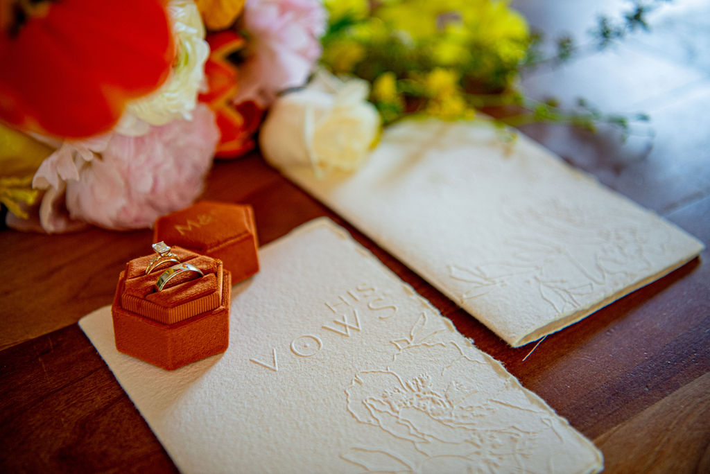 Beautiful flat lay images of the wedding rings, vow books and flowers put together by a Boulder wedding photographer.
