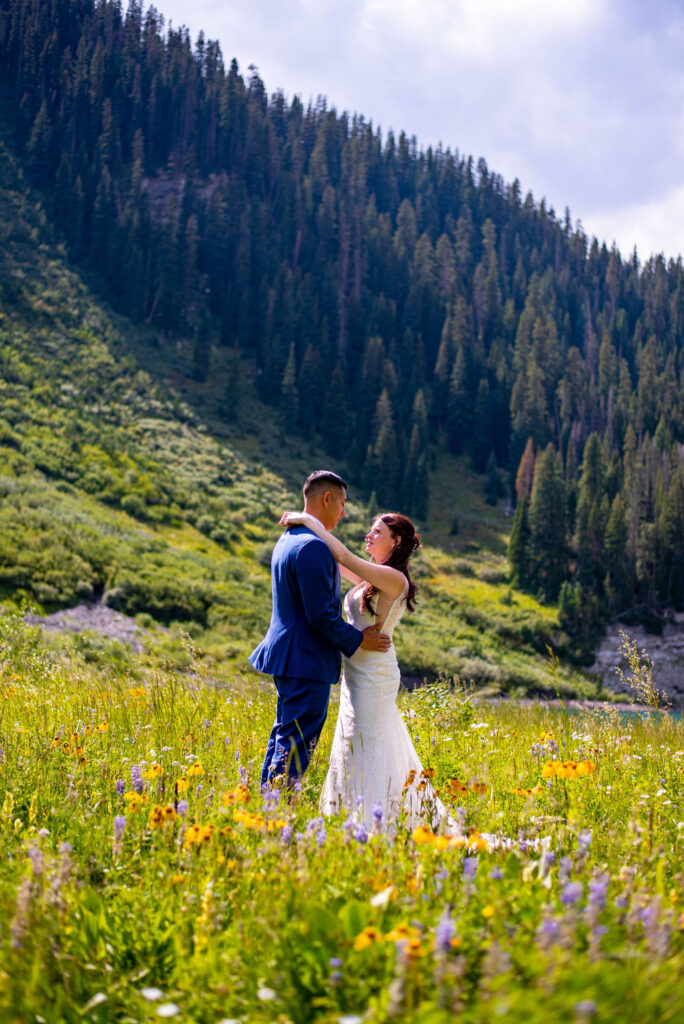bride and groom lovingly looking at each other while standing in a beautiful wildflower field in crested butte