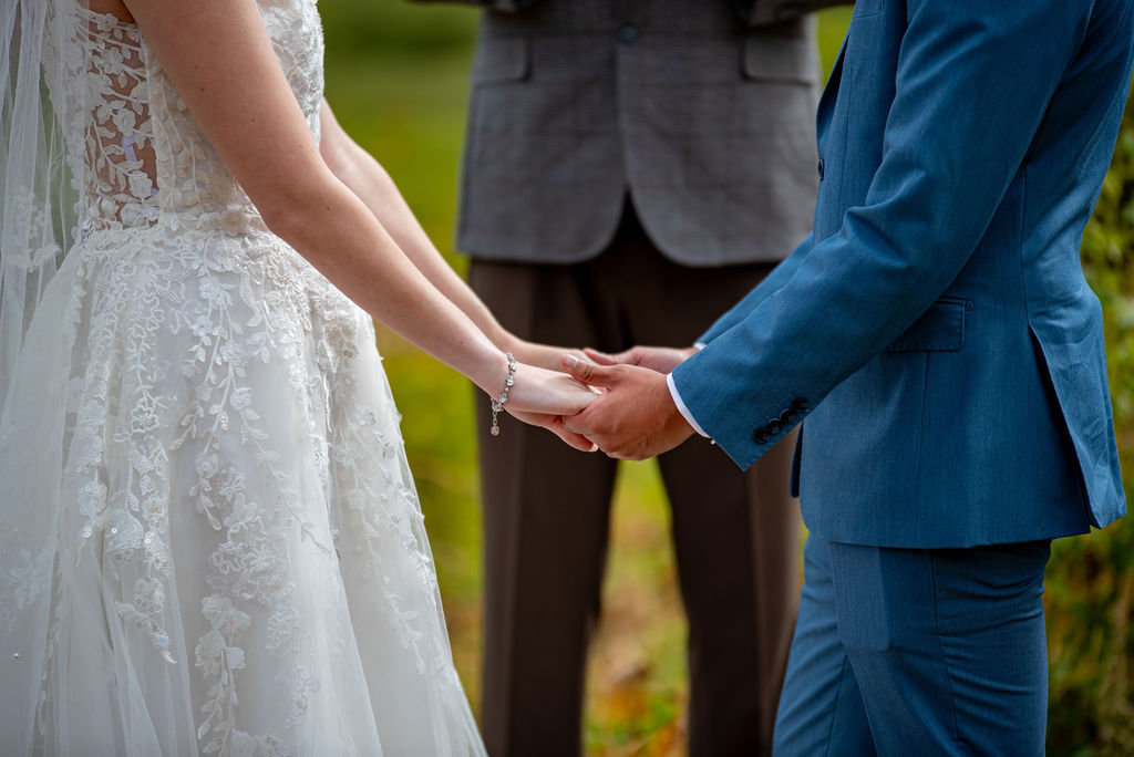 close up of bride and groom holding hands during their elopement ceremony as they legally elope in colorado