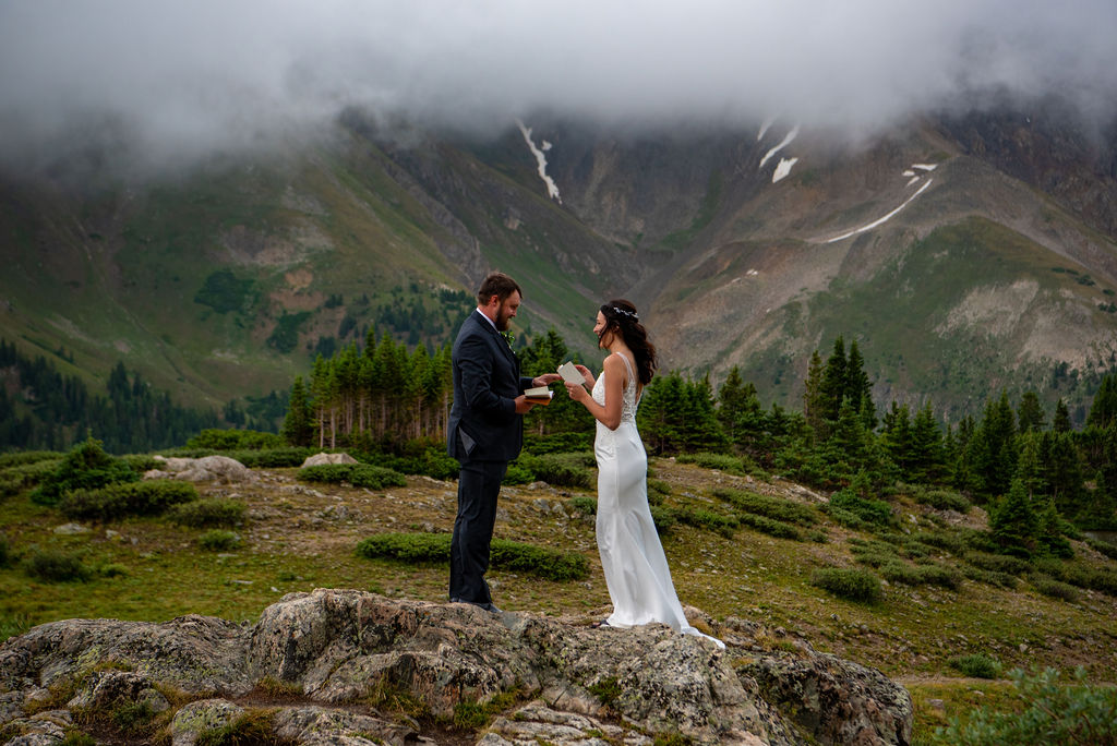 bride and groom reading vows to each other during their elopement ceremony with Colorado mountains in the backdrop