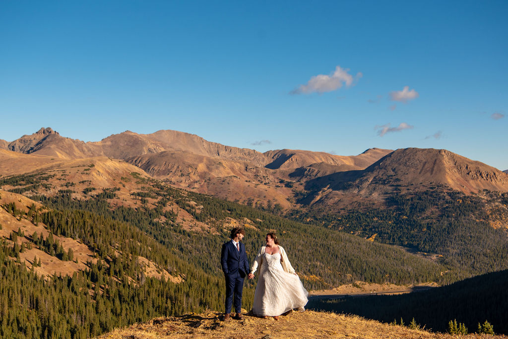 bride and groom holding hands surrounded by mountain views