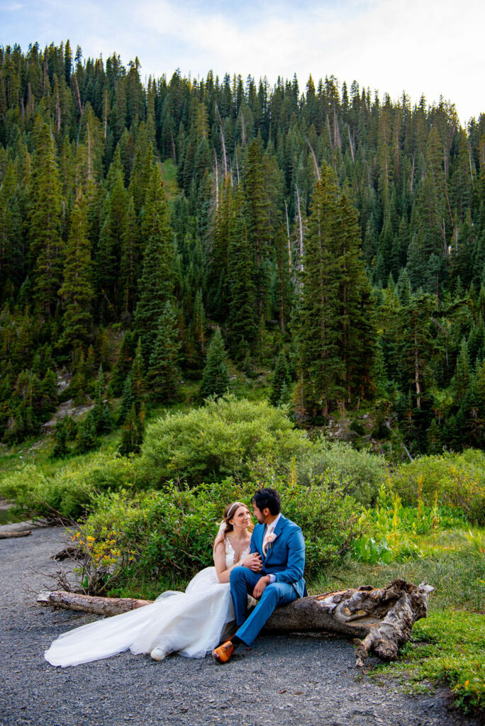 romantic bride and groom sitting down by an alpine lake