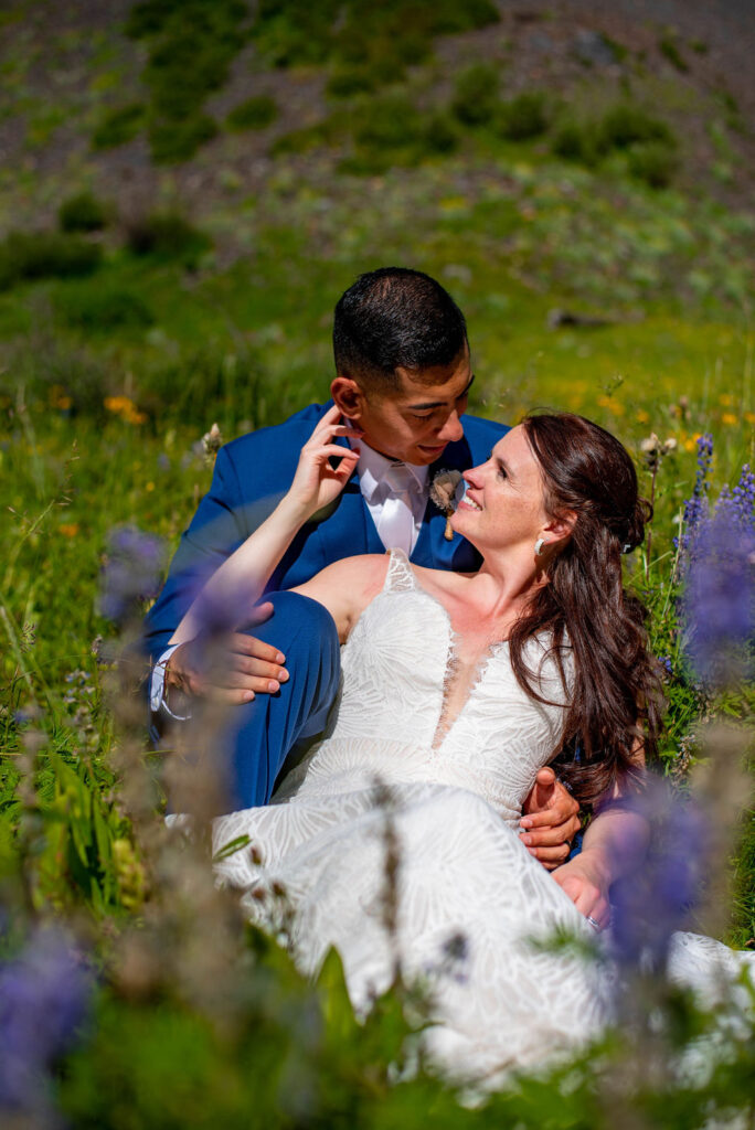 bride and groom sitting a wildflower field together