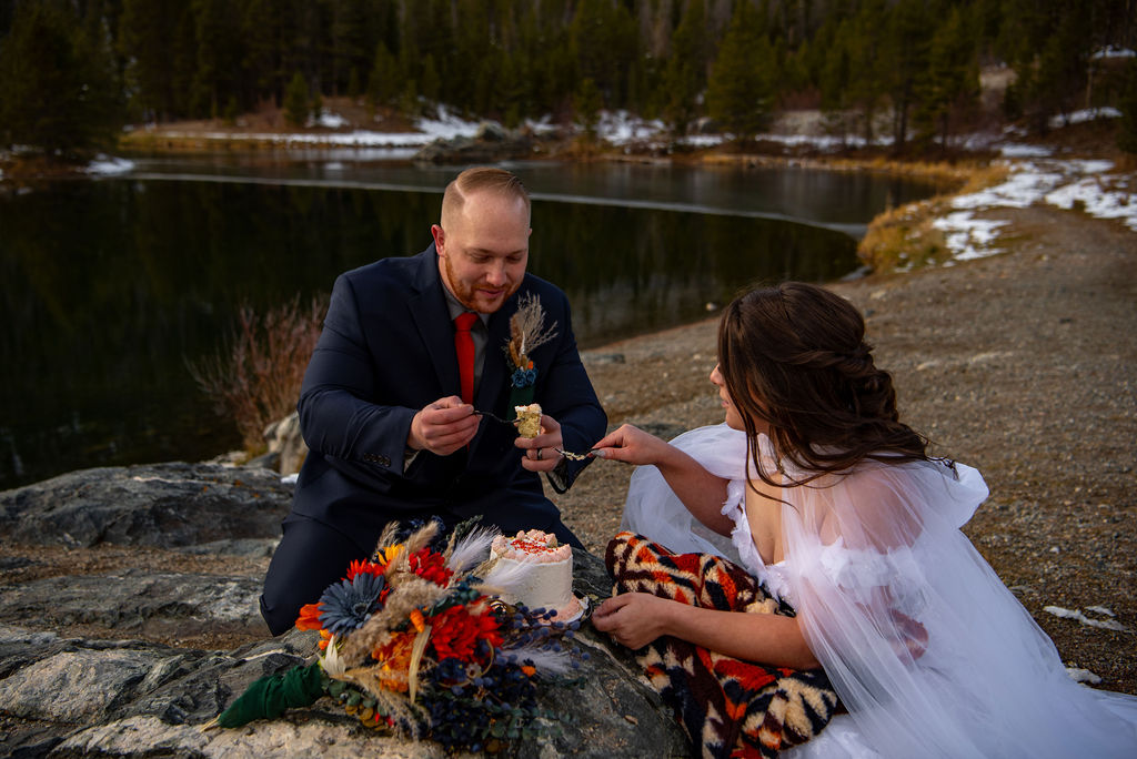 bride and groom eating a small cake during their elopement in colorado