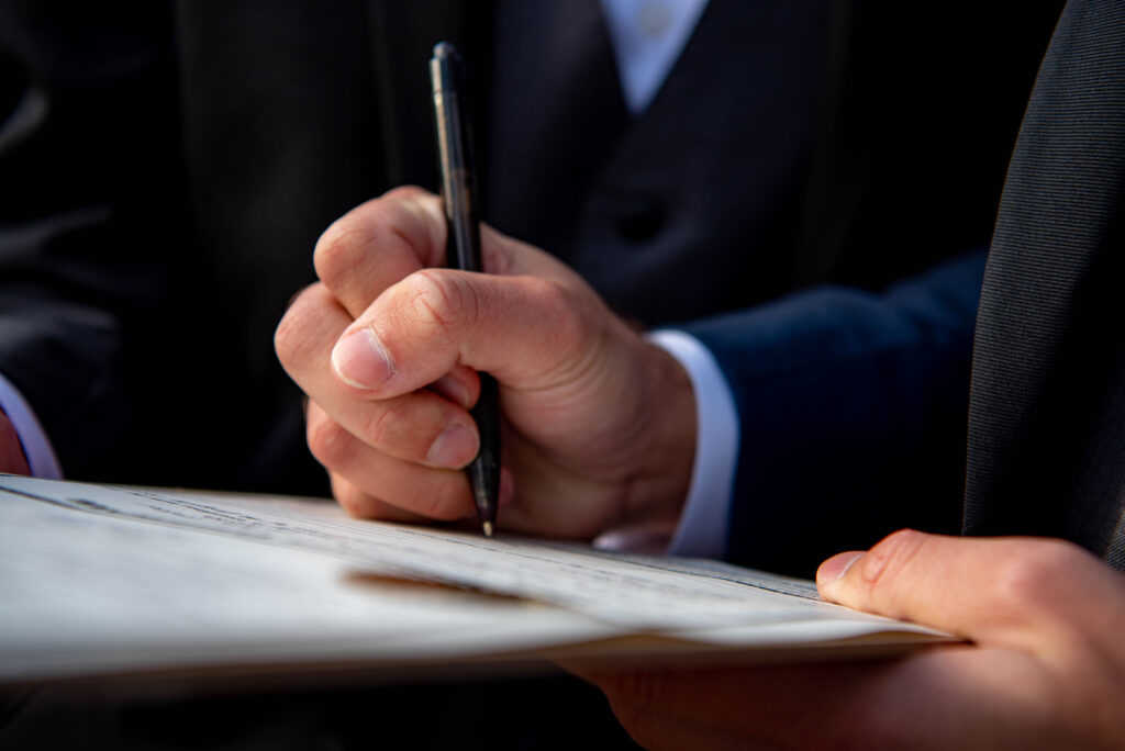 a close up of  the groom signing marriage license