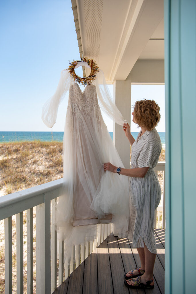bride looking at her wedding dress hanging on the balcony