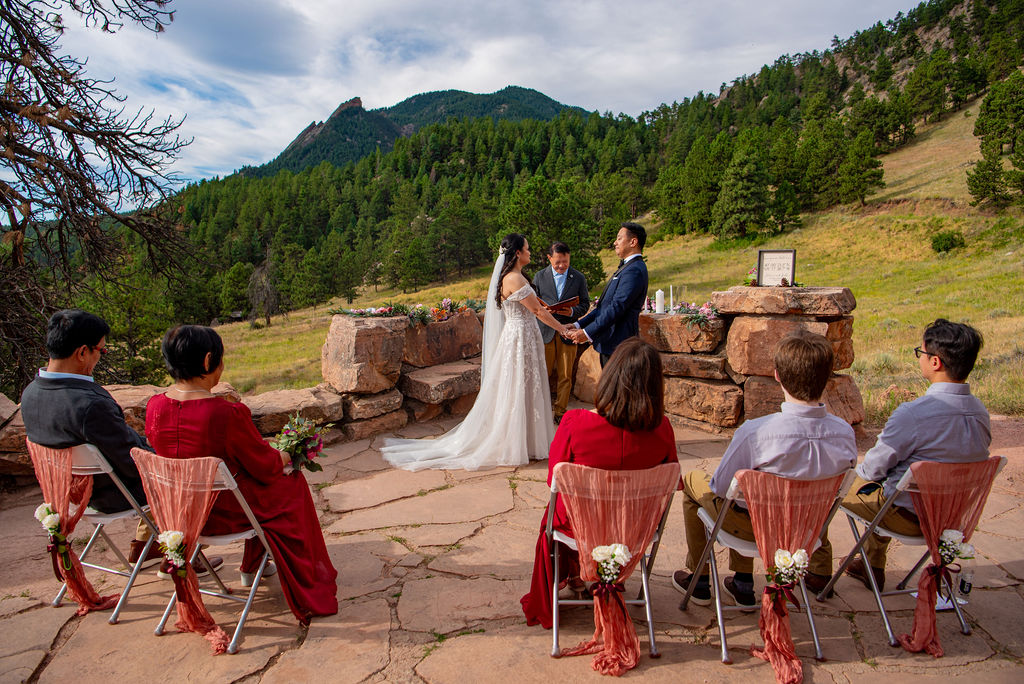 Bride and groom exchange vows during an intimate Boulder Halfway House wedding ceremony surrounded by close family and mountain views.