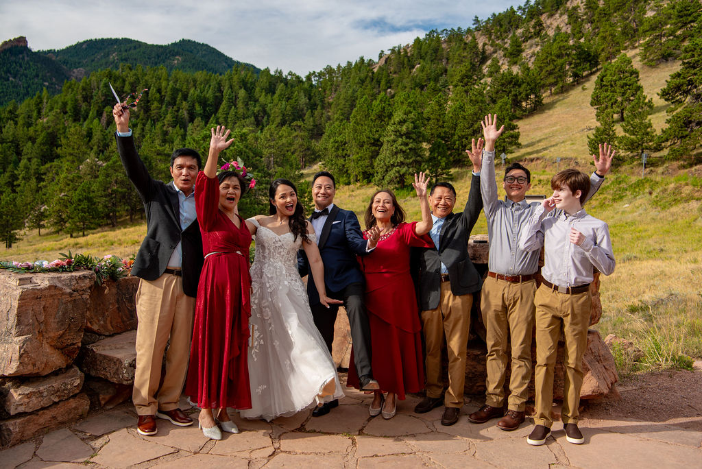 Wedding party celebrates with raised hands against scenic mountain backdrop during a joyful Boulder Halfway House wedding ceremony.