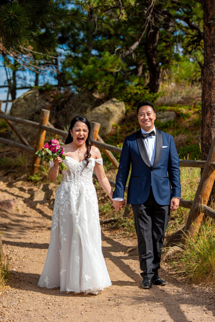 Bride and groom holding hands and walking joyfully on a dirt path near the Boulder Halfway House during their intimate wedding.