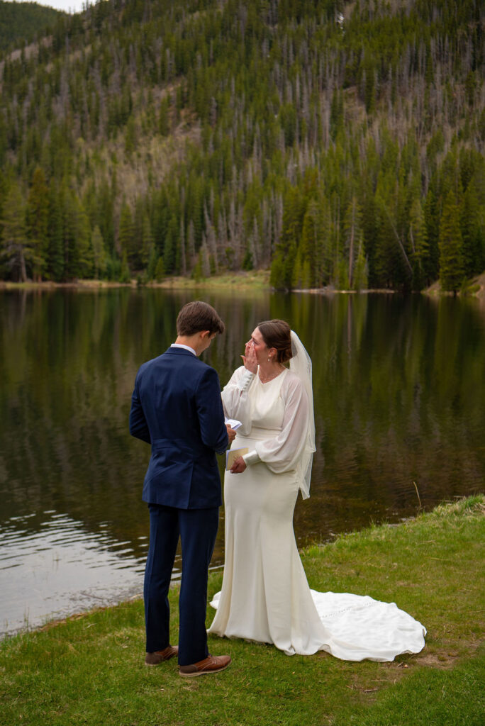 Example of how to plan an elopement ceremony with personal vows, featuring a couple exchanging heartfelt promises outdoors. The bride cries as the groom reads his vows.