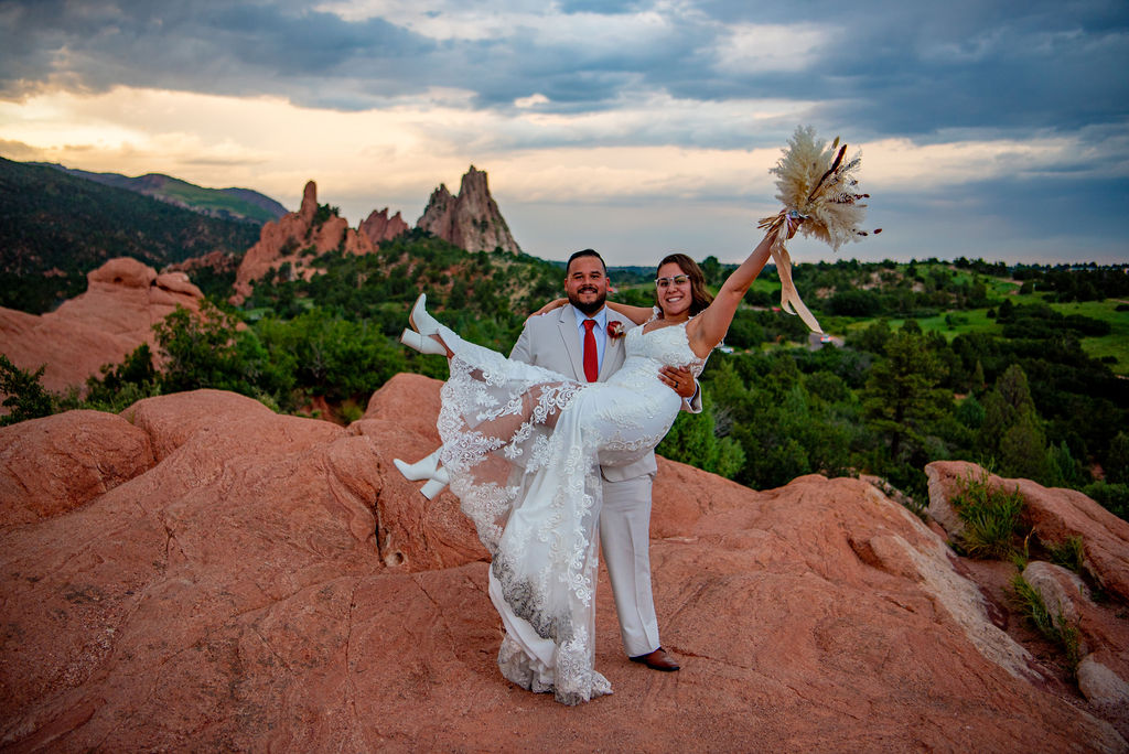 The bride and groom pose happily on rocky terrain at Garden of the Gods, a popular elopement destination in Colorado.