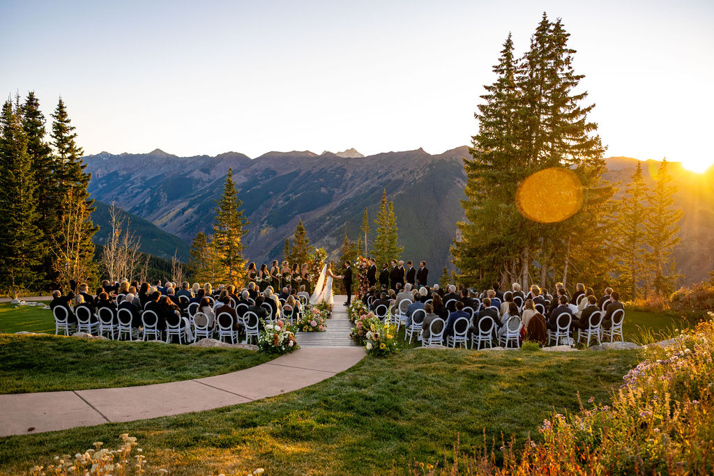 Couples exchanging vows at the summit of a ski lift in Aspen Colorado, surrounded by breathtaking mountains as the sunsets behind the couple, perfect for a Colorado wedding photographer.